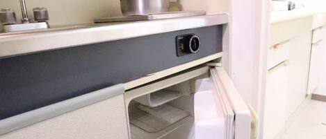 Una cocina compacta con horno integrado, un lavamanos y un refrigerador pequeño.