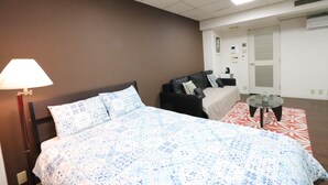 Hotellihuone, jossa on sänky, sohva, pieni pöytä ja lamppu.