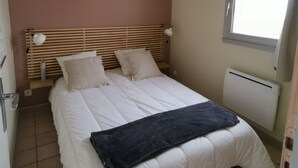 Un dormitorio con cama, ventana y radiador.