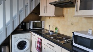 Cocina compacta con lavadora, microondas, estufa y un lavamanos pequeño.