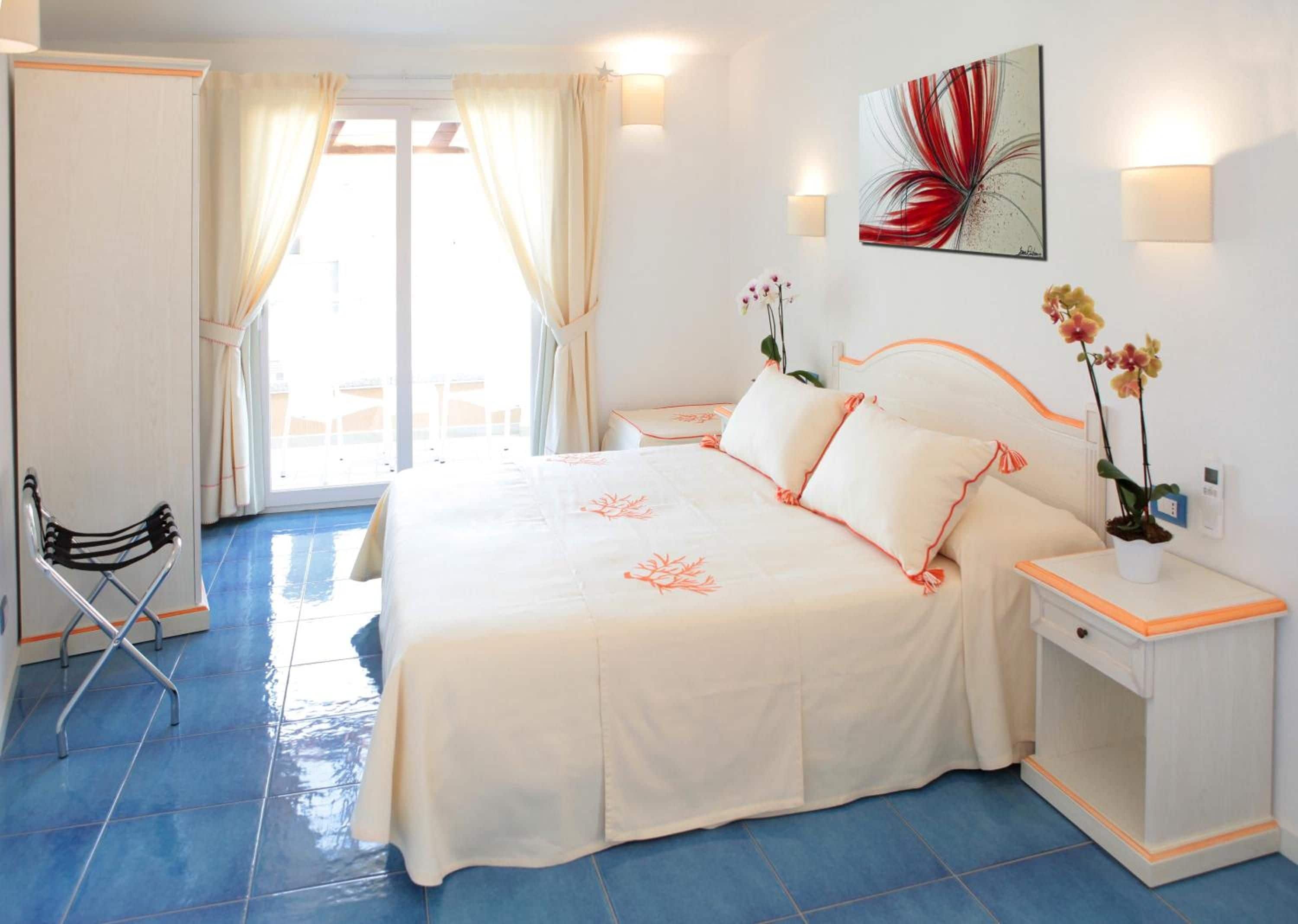 A hotel room with a bed, a nightstand, a chair, and a view of the outside.