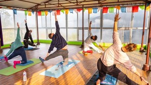 Ein Yoga-Kurs in einem Raum mit großen Fenstern und bunten Wimpeln.