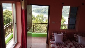 Ein Schlafzimmer mit Bett, einem Fenster mit Seeblick und einem Balkon mit Geländer.