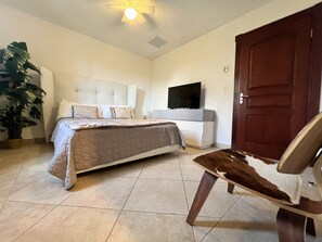 Ein Schlafzimmer mit Bett, Fernseher, Tür und Stuhl.