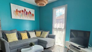 A modern living room with a grey sectional sofa, a white coffee table, and a flat-screen TV on a white stand.