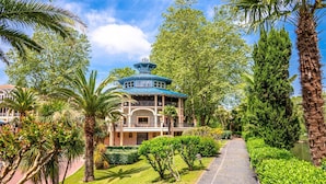A traditional-style building with a blue roof, surrounded by lush greenery and palm trees.