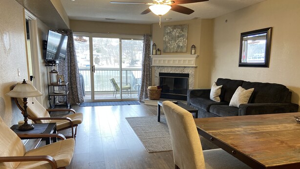 A spacious living room with a fireplace, a dining area, and a balcony with sliding glass doors. - Ledges Complex - Lake front With Slip Included - Beach and 2 Pools (Osage Beach)