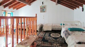 Quarto com teto de madeira, duas camas, um tapete grande e um corrimão de madeira.