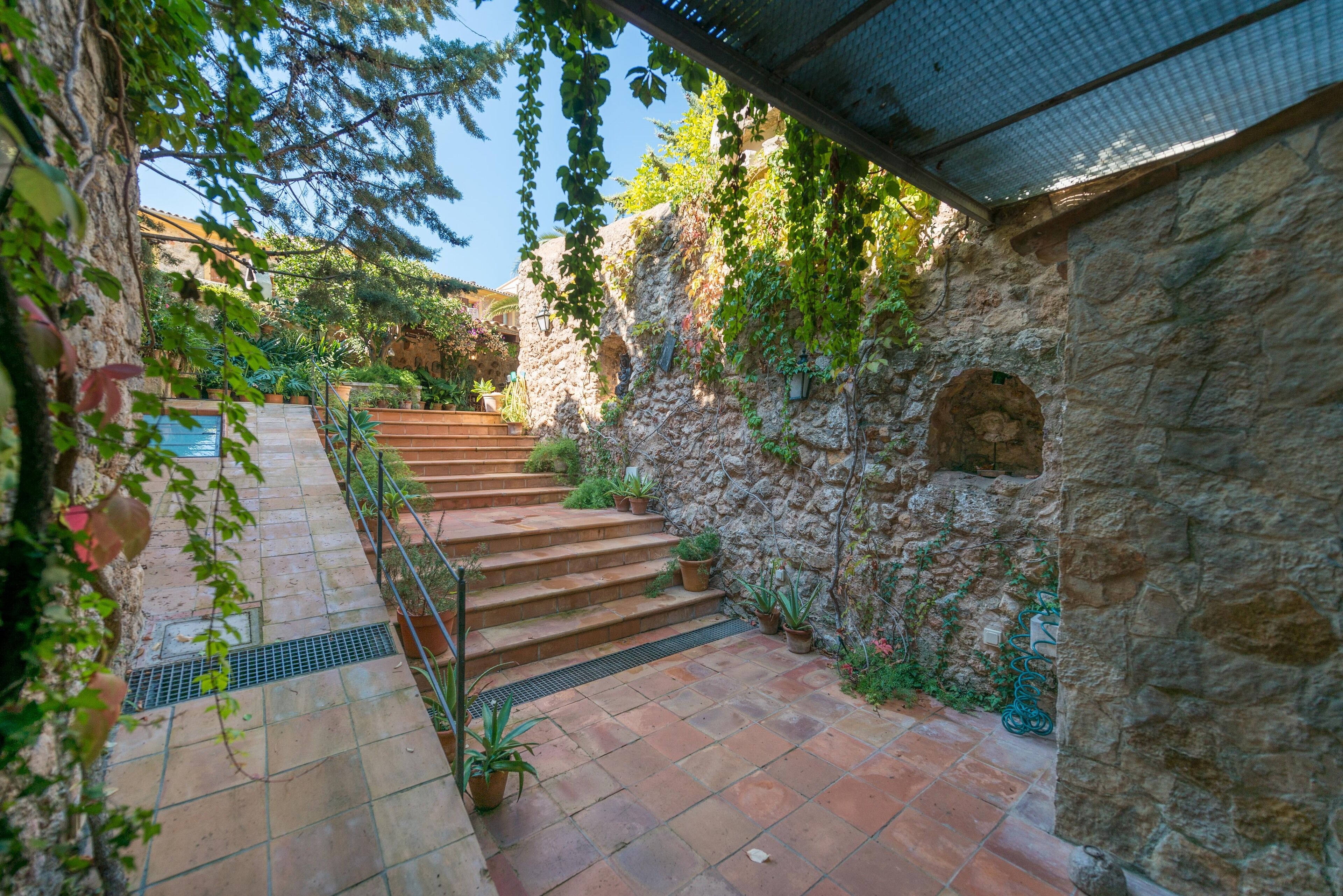 A stone staircase leading to a covered area with potted plants and a metal railing.