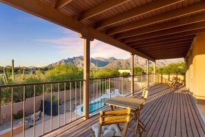 Eine Holzterrasse mit Pool, Stühlen und Bergblick.