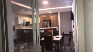 A modern kitchen with a central island, bar stools, and a dining area with a table and chairs. - EXCLUSIVE DEPARTMENT (Quito)