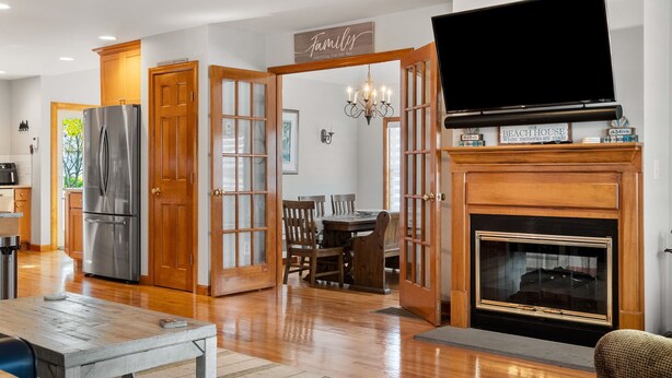 A spacious kitchen with a stainless steel refrigerator, wooden cabinets, and a dining area with a table and chairs. - York Beach Getaway (Razzle Dazzle House) (York)