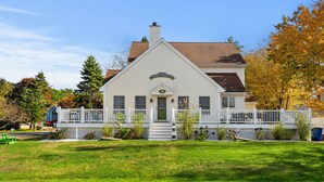 A two-story house with a white exterior, a front porch, and a small deck. - York Beach Getaway (Razzle Dazzle House) (York)