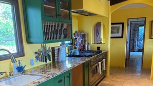 A kitchen with green cabinets, a granite countertop, and a tiled floor. - Vineyard Home for the Art Lover (Santa Ynez)