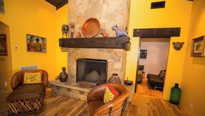 A cozy living room with a stone fireplace, leather armchairs, and various decorative items. - Vineyard Home for the Art Lover (Santa Ynez)