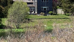 A two-story house with a dark exterior, a sloped roof, and a small porch with chairs. - TRANQUILITY IN NANTUCKET (Nantucket)