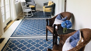 A covered porch with wicker chairs, a blue patterned rug, and an American flag on the wall. - TRANQUILITY IN NANTUCKET (Nantucket)