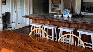 A modern kitchen with a wooden island, white bar stools, stainless steel appliances, and a ceiling fan. - TRANQUILITY IN NANTUCKET (Nantucket)