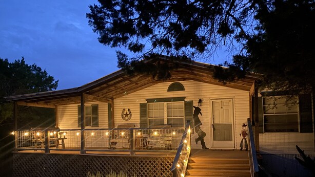 A rustic cabin with a wooden porch, a staircase, and a sign indicating it is a cottage. - Peaceful Hill Country Retreat • Private Hot Tub • 3½ Acres • Near Downtown (Wimberley)