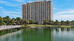A high-rise hotel with multiple balconies, a waterfront view, and a bridge connecting to the property. - Two Balconies, Sunset/Gulf View, Corner Unit (Destin)