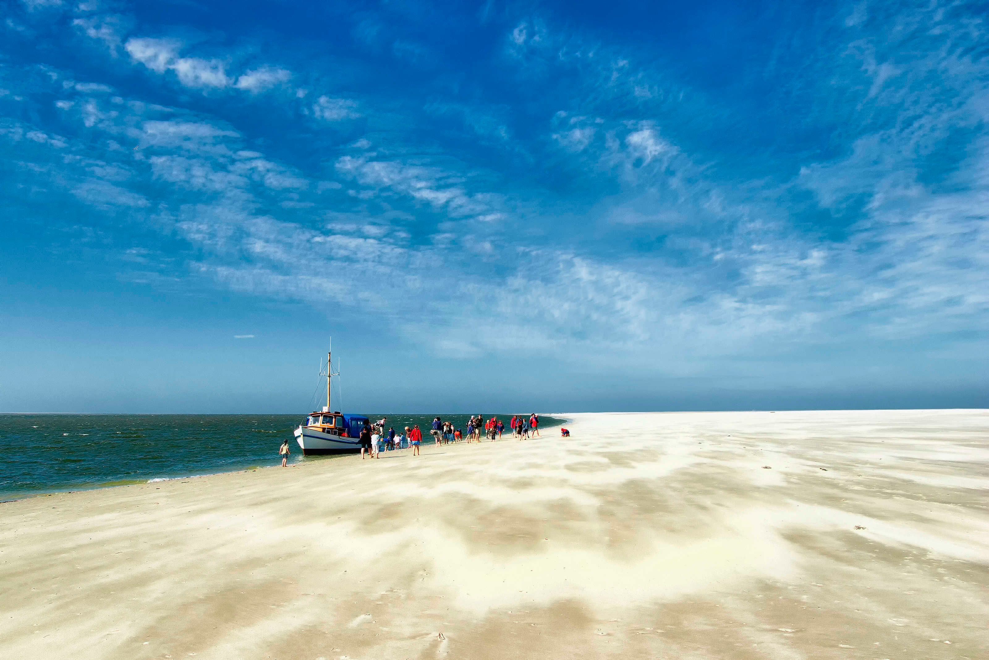 Une plage avec un bateau amarré, un ciel dégagé et une mer calme.