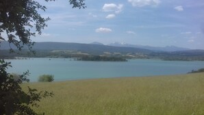 Un lac avec une étendue d’herbe au premier plan et des montagnes à l’horizon.