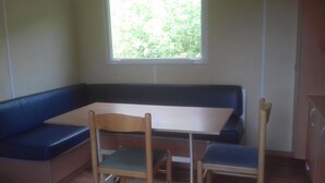 Une pièce avec un banc d’angle, une petite table et deux chaises.