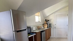 Una cucina con frigorifero in acciaio inox, mobili in legno, forno a microonde e finestra con persiane.