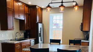 Una cucina con mobili in legno, un frigorifero in acciaio inossidabile, un piano di lavoro in granito e un lampadario.