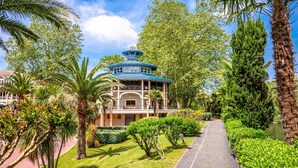 A traditional-style building with a blue roof, surrounded by lush greenery and palm trees.