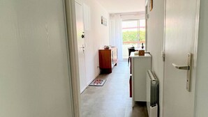 A narrow hallway with a radiator, a wooden cabinet, and a table with a vase.