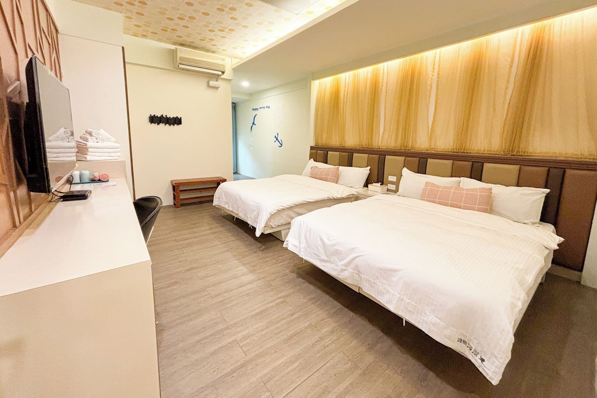 A hotel room with two beds, a desk, a mirror, and a wall with a 'Happy New Year' decoration.