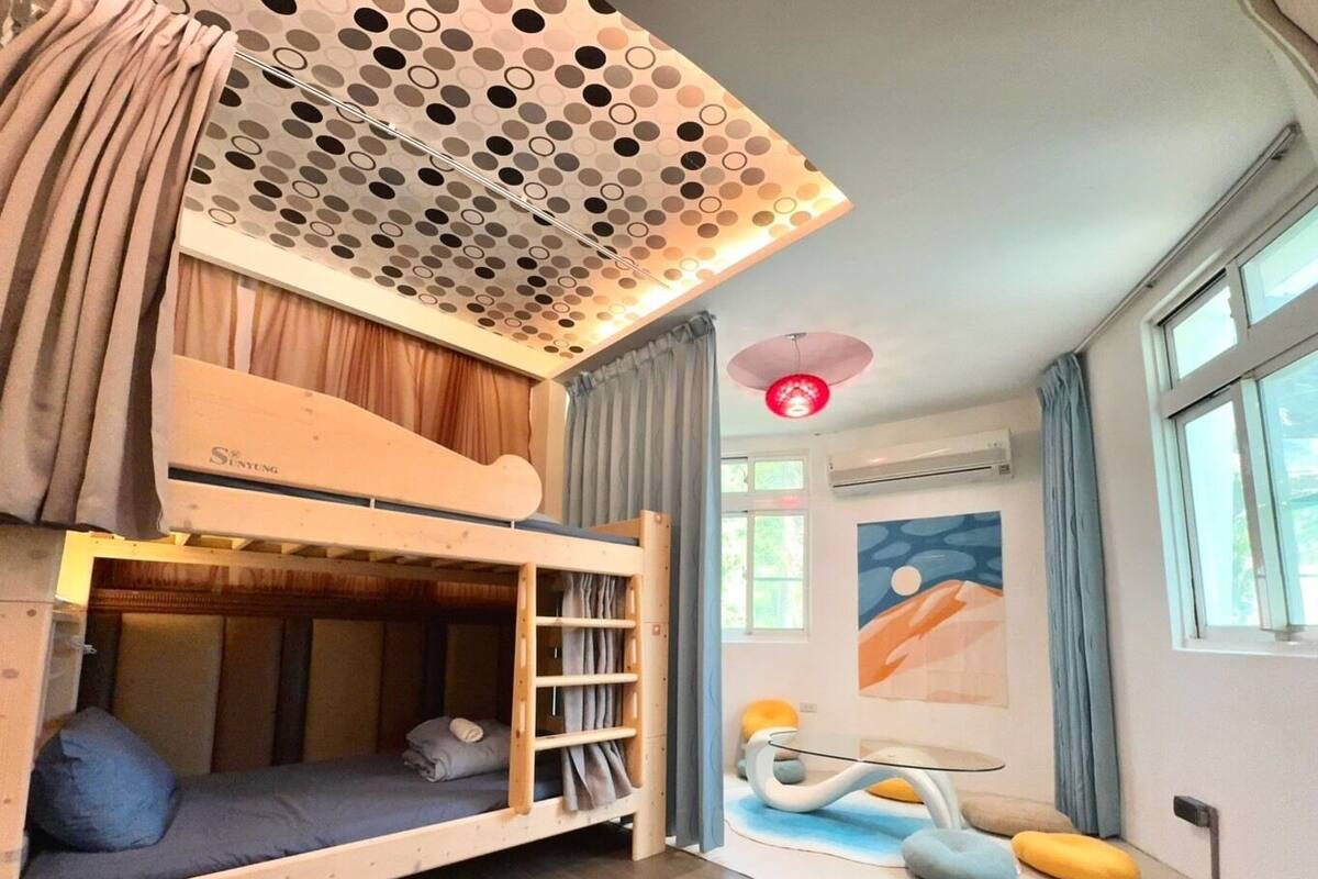A room with a bunk bed, a ceiling with circular patterns, a wall-mounted air conditioner, and a window with curtains.