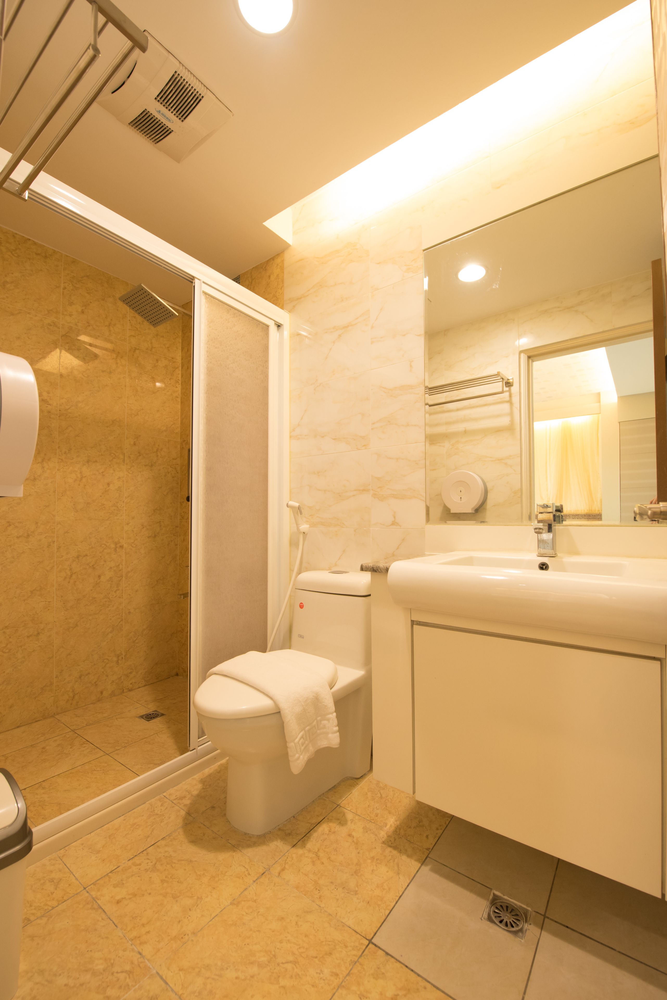 A bathroom with a shower, toilet, sink, and mirror.