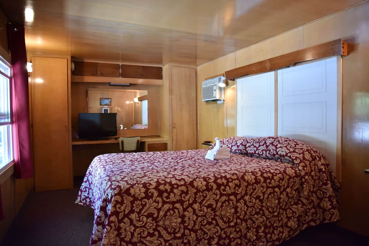 A bedroom with a bed, a television, a desk, and a wardrobe.