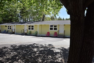 Filas de habitaciones de motel con una galería techada y asientos exteriores.