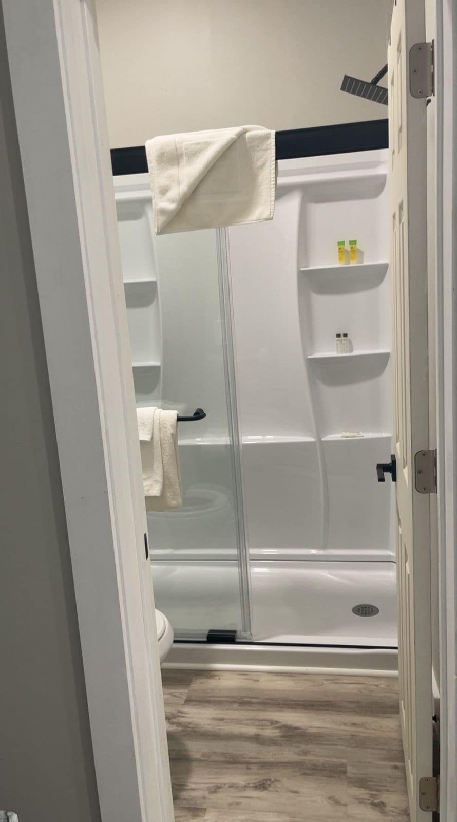 Kylpyhuone, jossa on kylpyamme, pyyheteline ja hyllyjä, joilla on hygieniatuotteita.