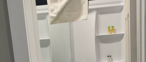 A bathroom with a bathtub, a towel rack, and shelves with toiletries.