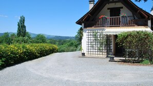 A traditional chalet with a sloped roof, wooden balcony, and a gravel driveway leading to the entrance. - Charming Small Cottage in Soule (MENDITTE)
