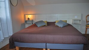 A double bed with a wooden frame, two bedside tables with lamps, and a headboard with storage compartments. - Charming Small Cottage in Soule (MENDITTE)