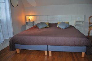 A double bed with a wooden frame, two bedside tables with lamps, and a headboard with storage compartments. - Charming Small Cottage in Soule (MENDITTE)