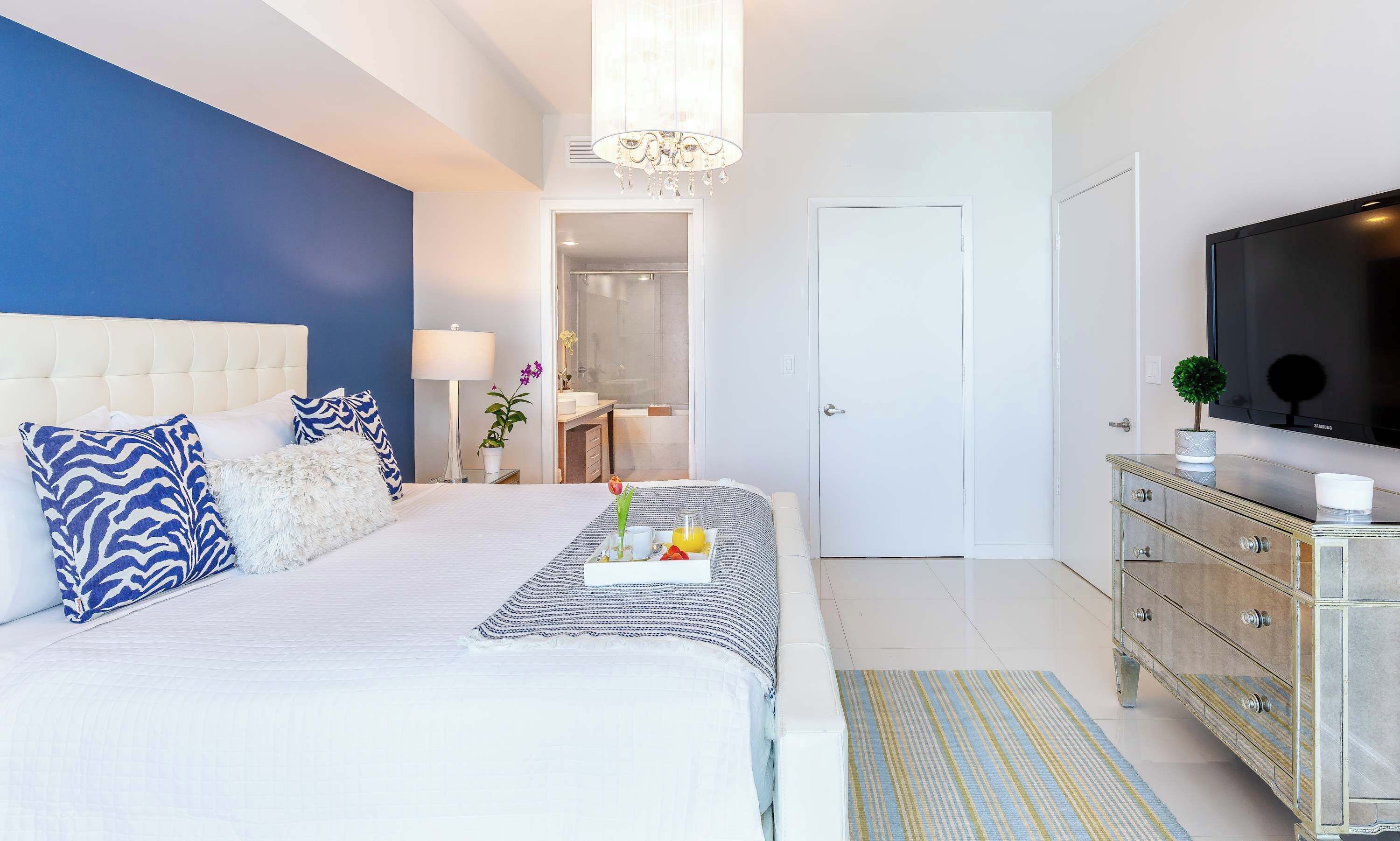 Een moderne slaapkamer met een groot bed, een televisie en een dressoir.
