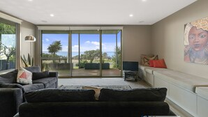 A modern living room with a large sliding glass door leading to a balcony with a view of the sea. - Grossard Point The Lighthouse Ventnor (Ventnor)