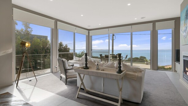 A modern living room with a large glass wall, a white sofa, a small table, and a telescope. - Grossard Point The Lighthouse Ventnor (Ventnor)