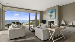 A modern living room with a large glass door leading to a balcony overlooking the sea. - Grossard Point The Lighthouse Ventnor (Ventnor)