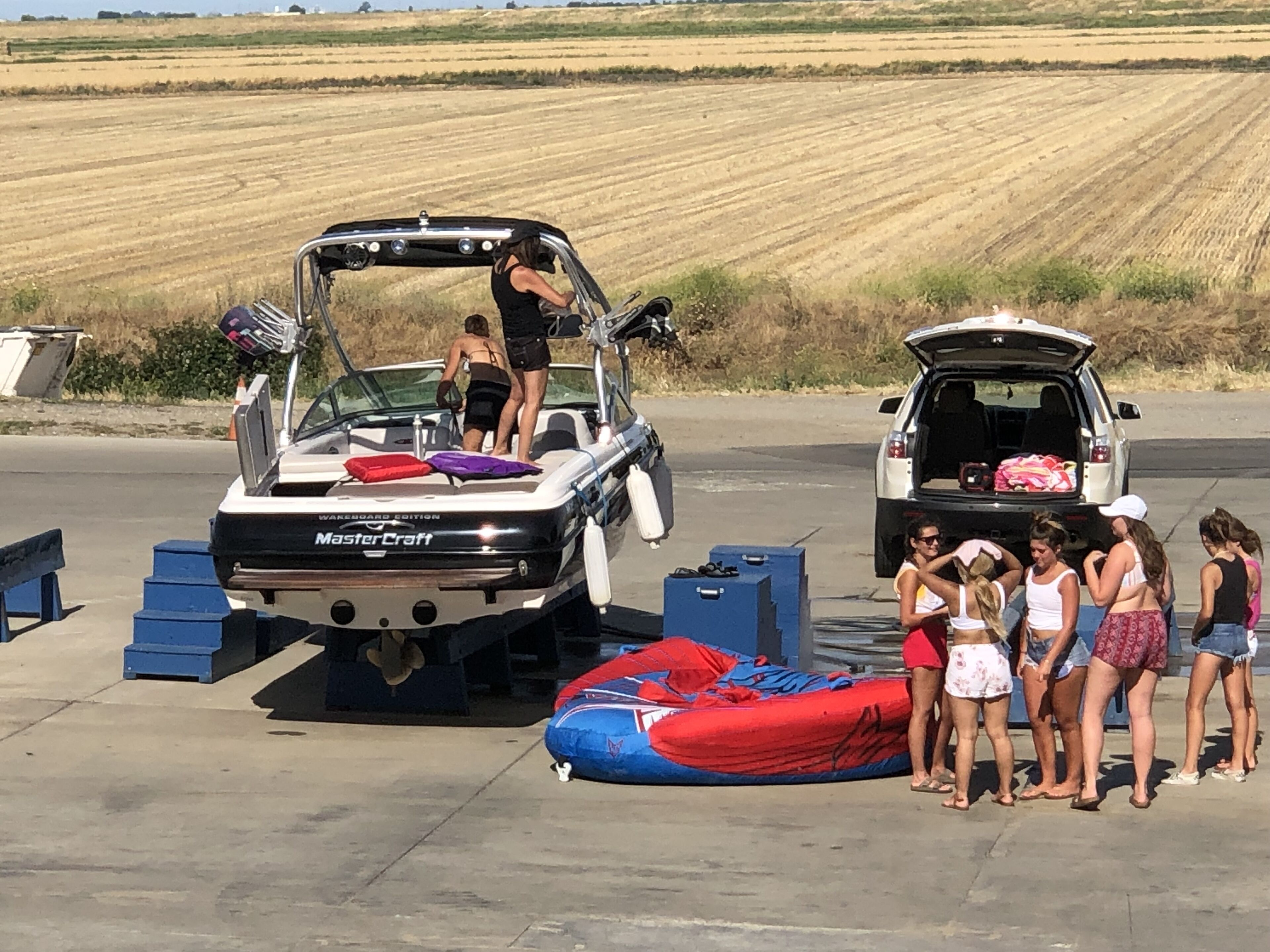 A boat with a canopy, a trailer, and a group of people standing by.