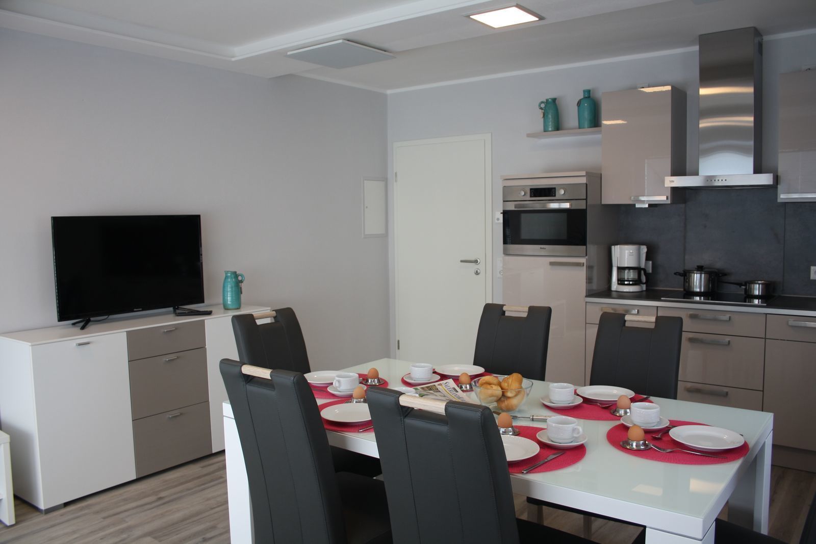 Cocina moderna con comedor, que incluye un televisor de pantalla plana, un microondas y una cafetera.