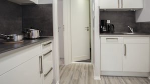 A compact kitchen with white cabinets, a microwave, a coffee maker, and a sink. - Ferienpark Winterberg (Winterberg)