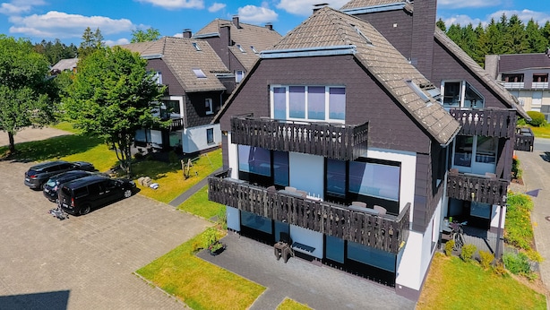A modern two-story house with a balcony, a driveway with cars, and a well-maintained lawn. - Ferienpark Winterberg (Winterberg)