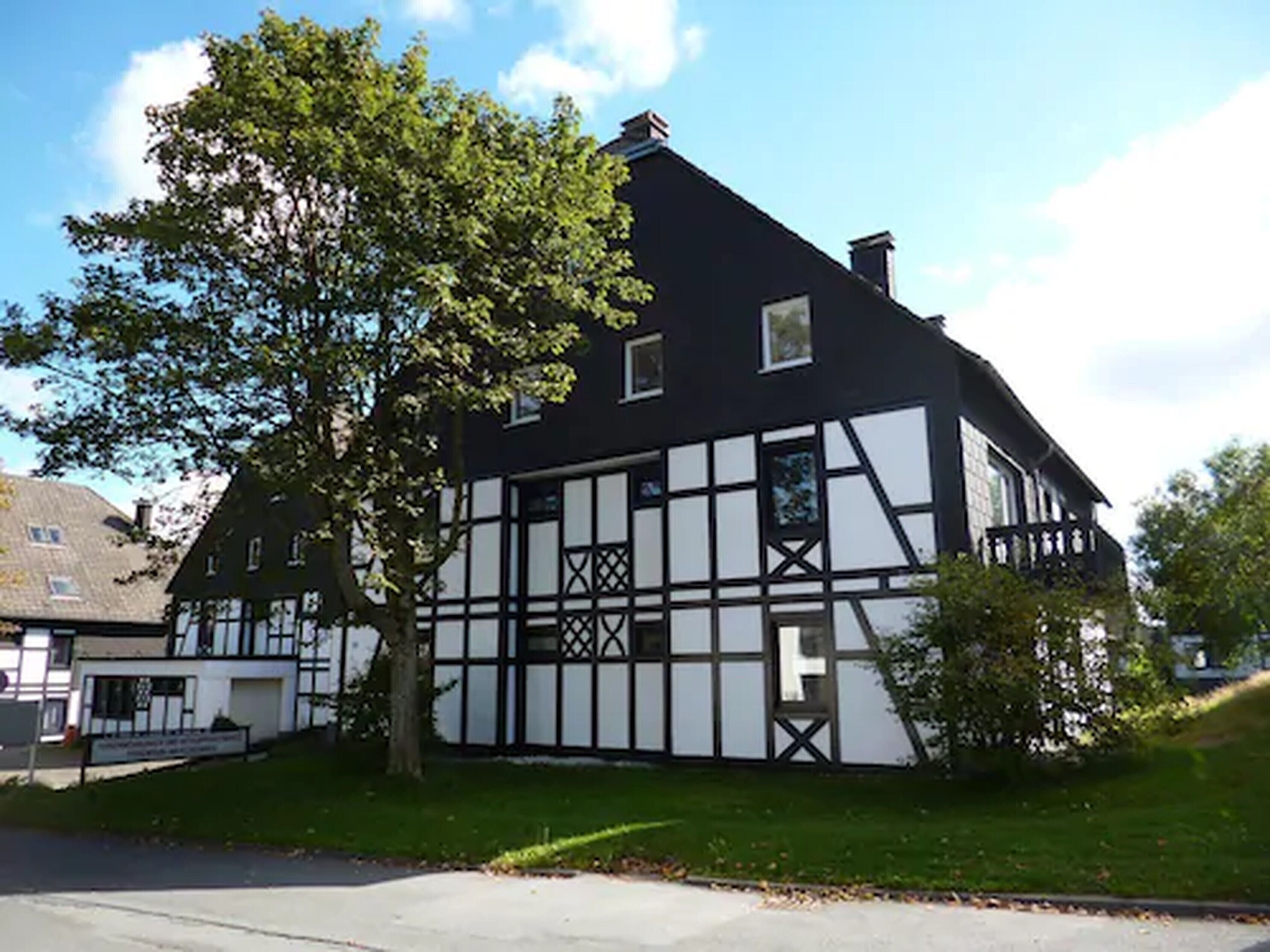 A traditional half-timbered house with a steep gabled roof, a visible chimney, and a well-maintained lawn.